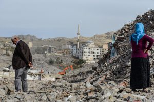 People stand amidst the rubble in Sirnak city on November 14, 2016, after a 246-day curfew was partially lifted. / AFP PHOTO / ILYAS AKENGIN