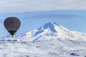 NEVSEHIR, TURKEY - JANUARY 06: A hot air balloon flies over snow covered Cappadocia, a historical region in Central Anatolia, largely in Nevsehir Province, known for the fairy chimneys, during the winter season on January 06, 2017 in Nevsehir, Turkey. Sercan Kucuksahin / Anadolu Agency