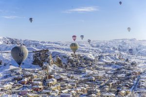 NEVSEHIR, TURKEY - JANUARY 06: Hot air balloons fly over snow covered Cappadocia, a historical region in Central Anatolia, largely in Nevsehir Province, known for the fairy chimneys, during the winter season on January 06, 2017 in Nevsehir, Turkey. Sercan Kucuksahin / Anadolu Agency