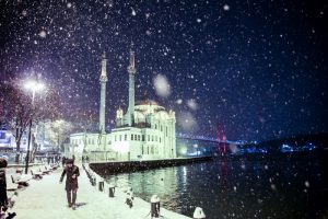People are seen around the Ortakoy mosque in snow covered street during the heavy snowfall in Istanbul's Ortakoy district, Turkey on January 07, 2017. Berk Ozkan / Anadolu Agency