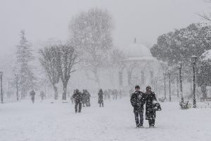 People walk at Sultanahmet square during snowfalls in Istanbul on January 8, 2017. / AFP PHOTO / YASIN AKGUL