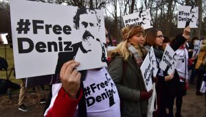 People hold placards with hashtag #FREEDENIZ to protest the detantion of German journalist Deniz Yucel in front of Turkish embassy in Berlin on February 28, 2017.  The investigative detention against Yuecel in Turkey has sparked indignation in the government, parties, and journalist associations in Germany. Yucel, 43, was detained on February 18 and his apartment searched in connection with news reports on an attack by hackers on the email account of Turkey's energy minister. Yucel originates from Floersheim. / AFP PHOTO / John MACDOUGALL