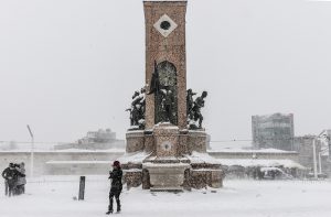 People walk at Taksim square during snowfalls in Istanbul on January 7, 2017. / AFP PHOTO / YASIN AKGUL